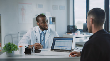 African American Medical Doctor is Explaining Diagnosis to a Patient on a Computer in a Health Clinic. Medical Health Care Professional Showing Test Results, Patient Treatment Planning.; Shutterstock ID 1908881998; purchase_order: -; job: -; client: -; other: -