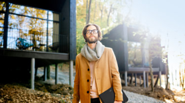 Portrait of a handsome man architect standing with laptop in front of the modern houses in the forest; Shutterstock ID 1204925668; Purchase Order: -